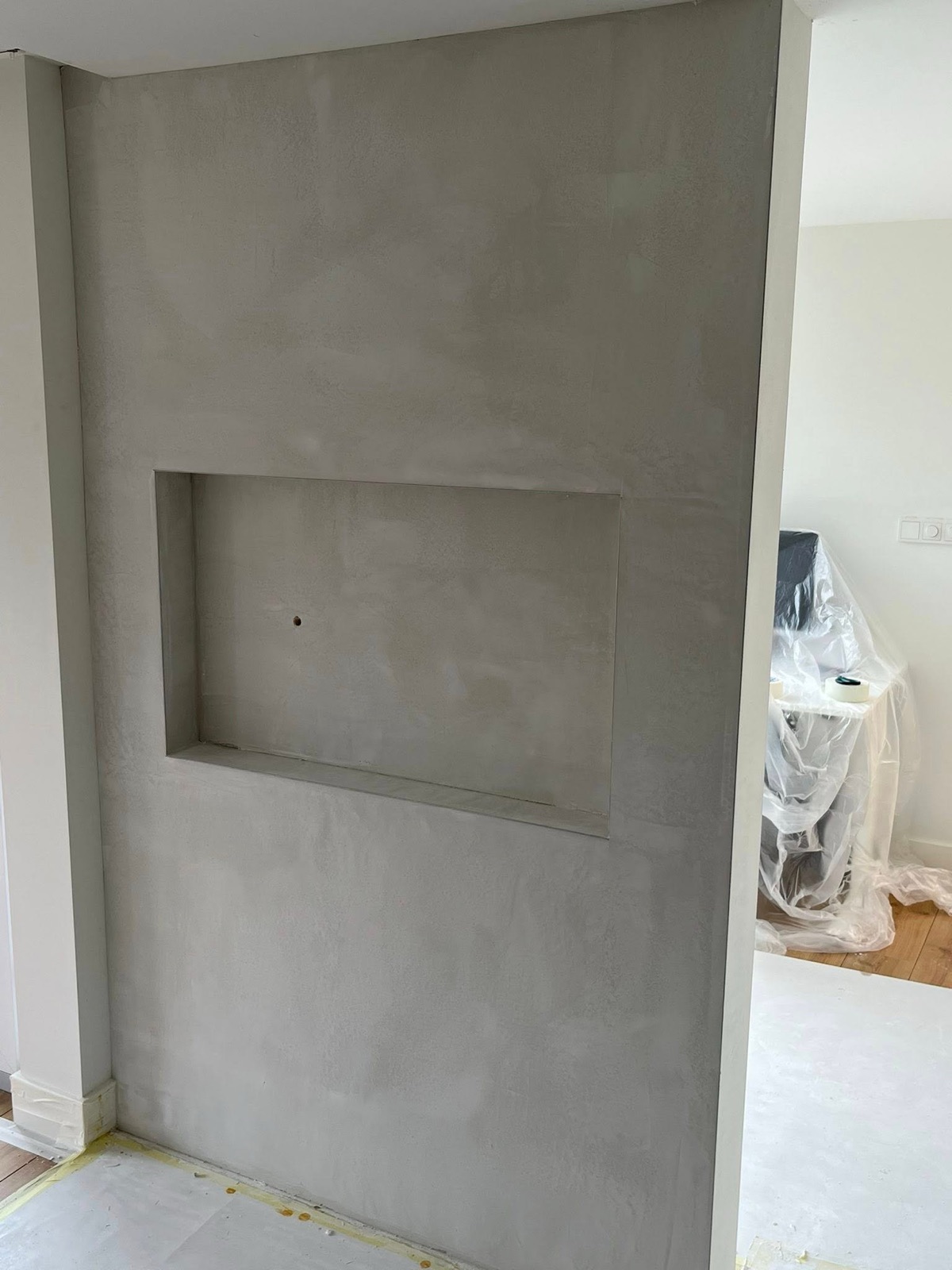 Strak gestucte grijze wand met een nis
